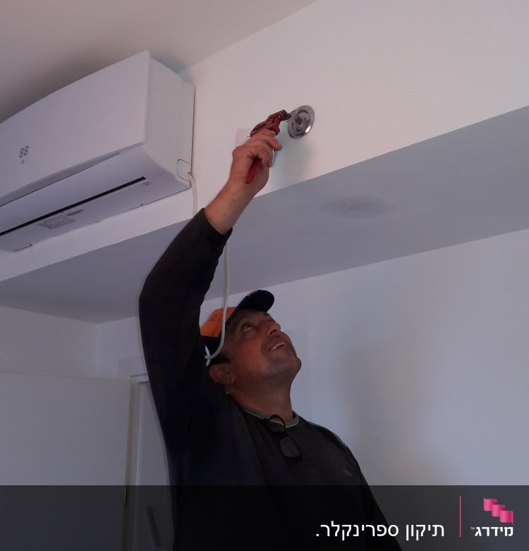 אדם משתמש במפתח צינורות לתיקון צינור